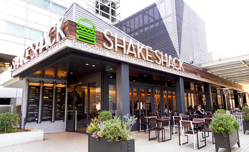Shake Shack restaurant exterior featuring its signature burger logo and outdoor seating, illustrating the brand’s planned entry into Brazil through a master franchise partnership with Bold Hospitality.